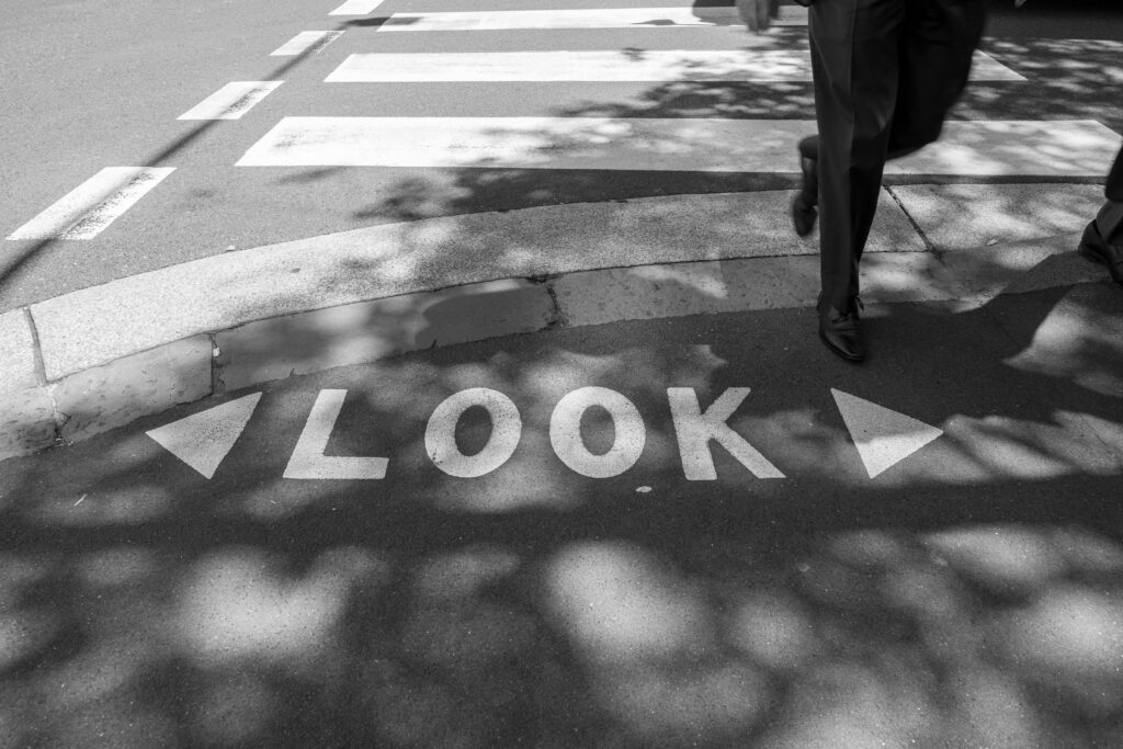 A shadowed city crosswalk in Sydney, NSW, with 'look' painted on the sidewalk.