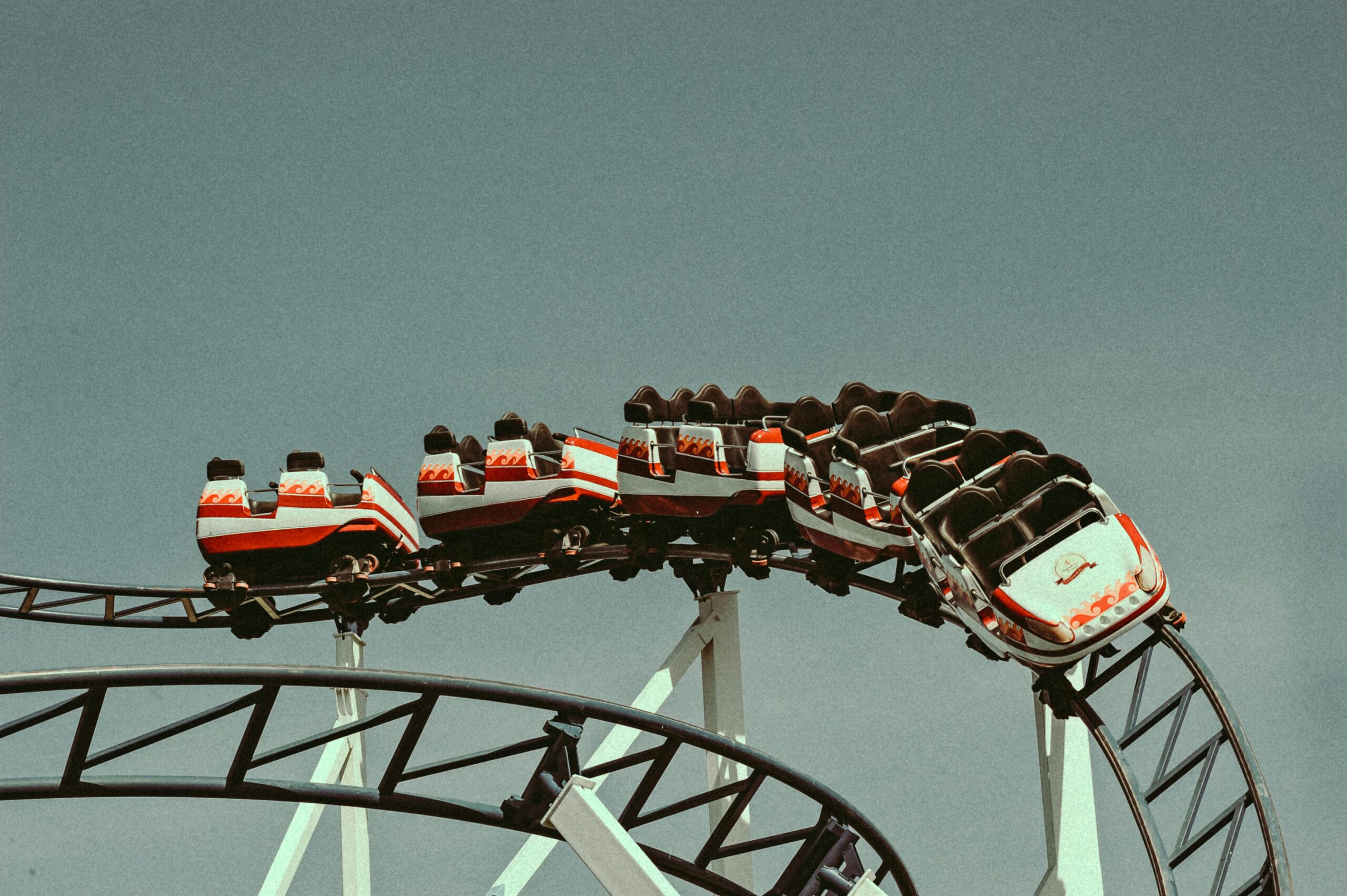A striking view of a roller coaster ride with vintage cars in action against a clear sky.