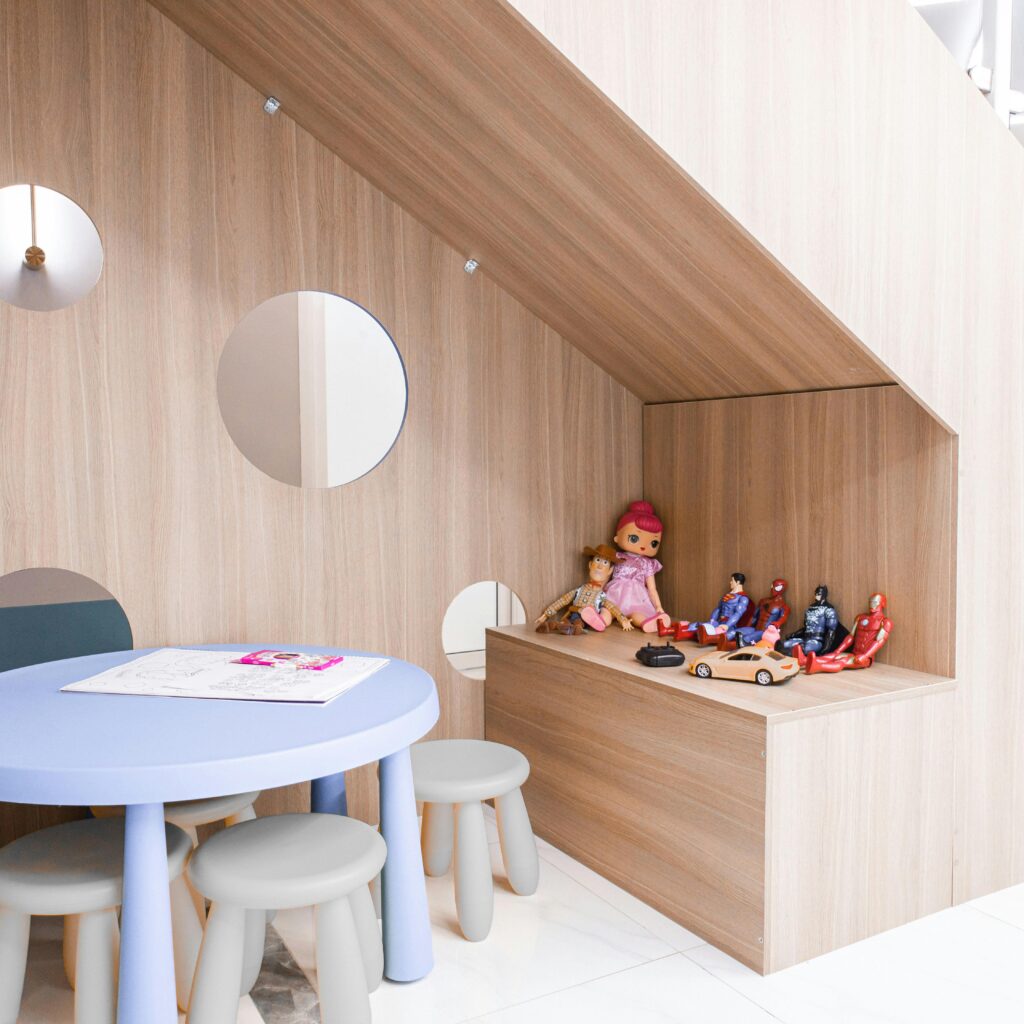 A stylish playroom with round table, stools, and toys, ideal for modern preschools.