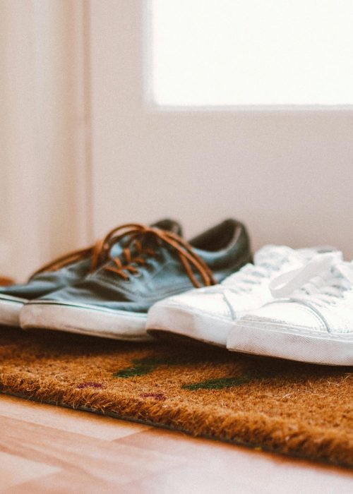 Cozy family shoes on a doormat at home entrance, symbolizing warmth and connection.